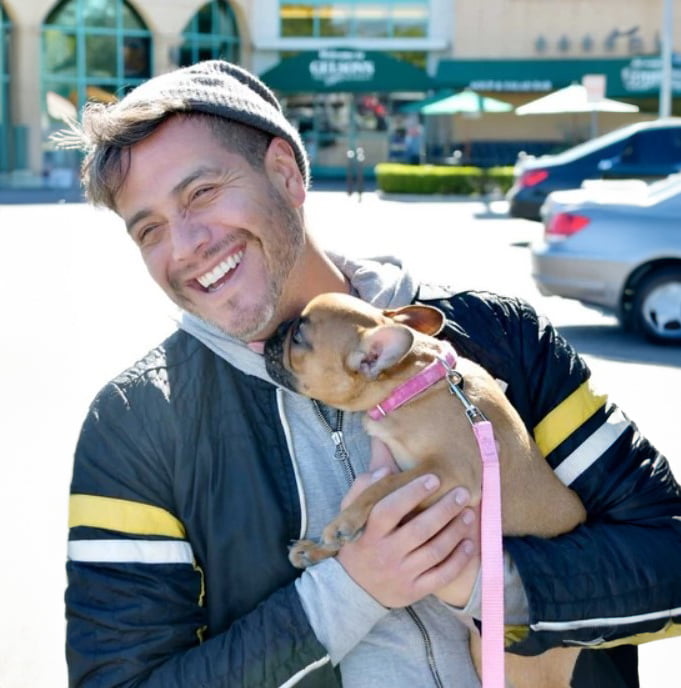 Anthony Silva, celebrity dog trainer owner of Core Dog training services holding a small dog in a pink collar.